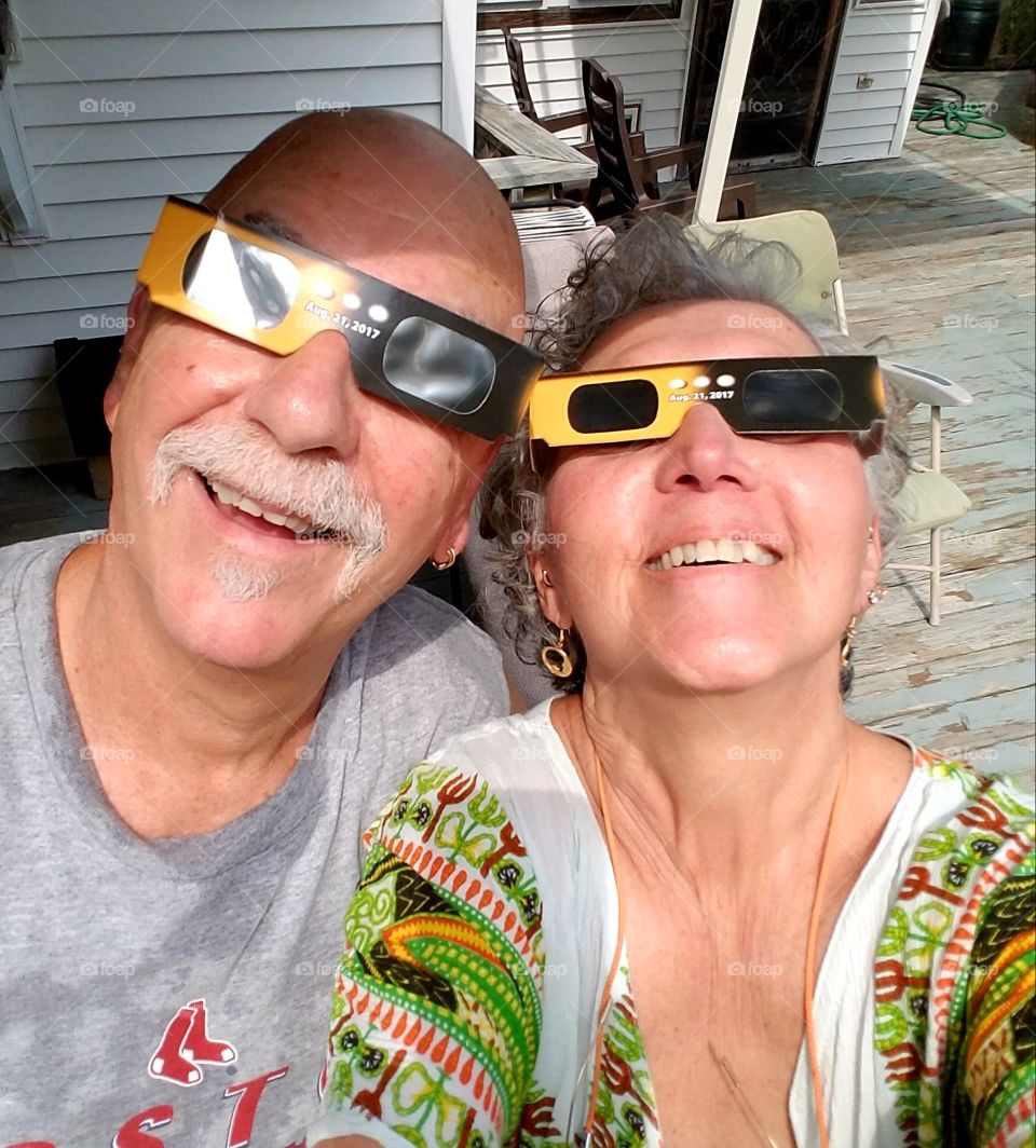 Couple watching Solar Eclipse,  happy, solar glasses on.