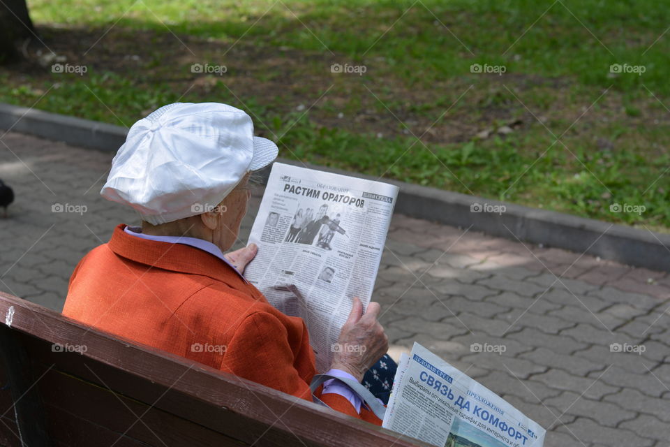 woman reading on a street bench in the park summer time