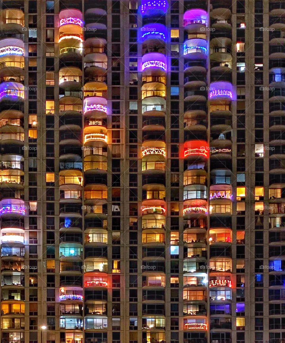 Windows and balconies decorated with Christmas lights in a high-rise apartment building 