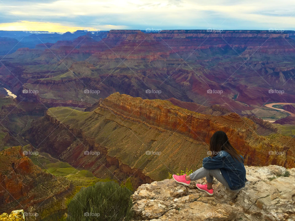 A young Woman sitting on the precipice before the grand canyon,ARIZONA