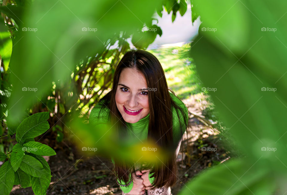 Portrait of beautiful young girl surrounded by green leaves