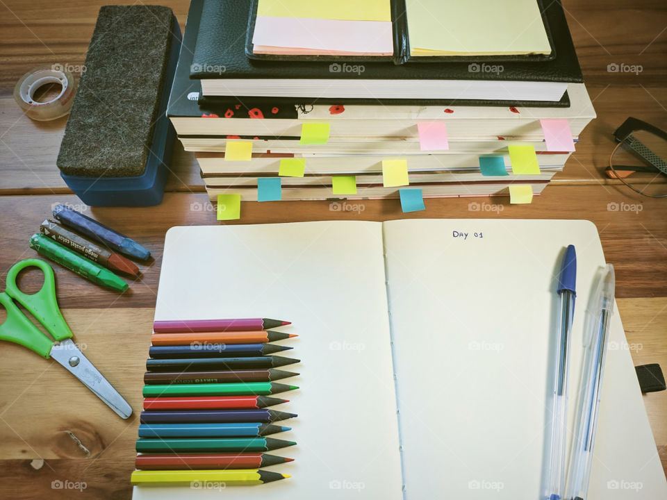 A notebook written day one, several colored pencils and books with post it to mark important pages to study, crayons, scissor, eraser... all ready to start to study 