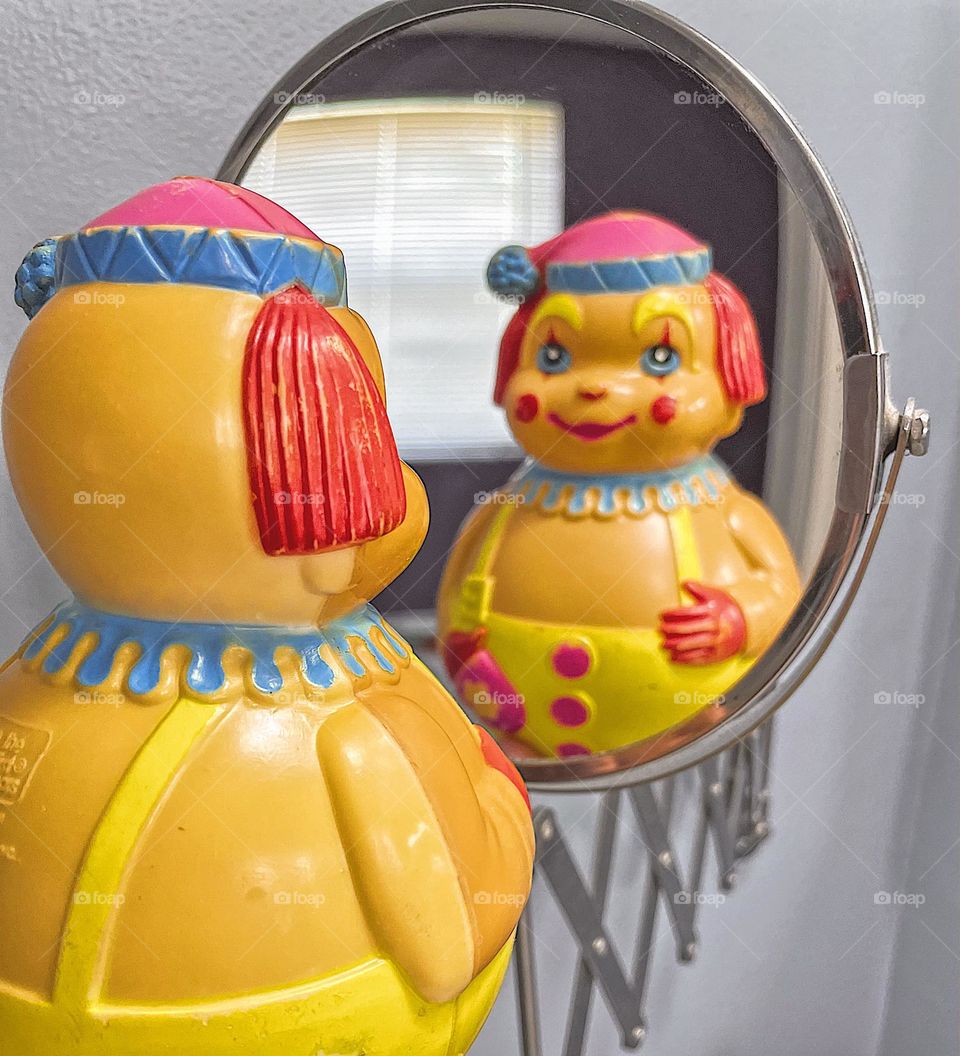 Clown toy reflection in makeup mirror, clown looking at reflection in the mirror, clown reflection in mirror, vintage clown toy reflection, reflections of clowns, silly clown reflections 