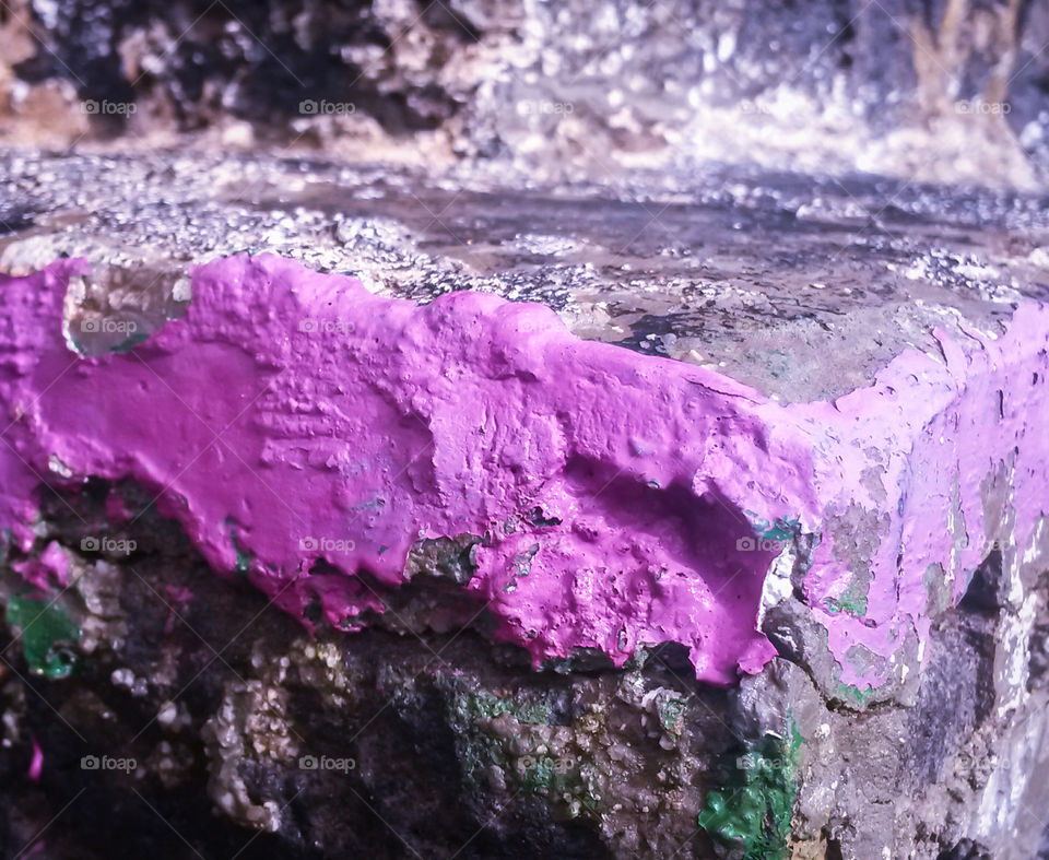 detail of a granite wall in an old building painted with purple color