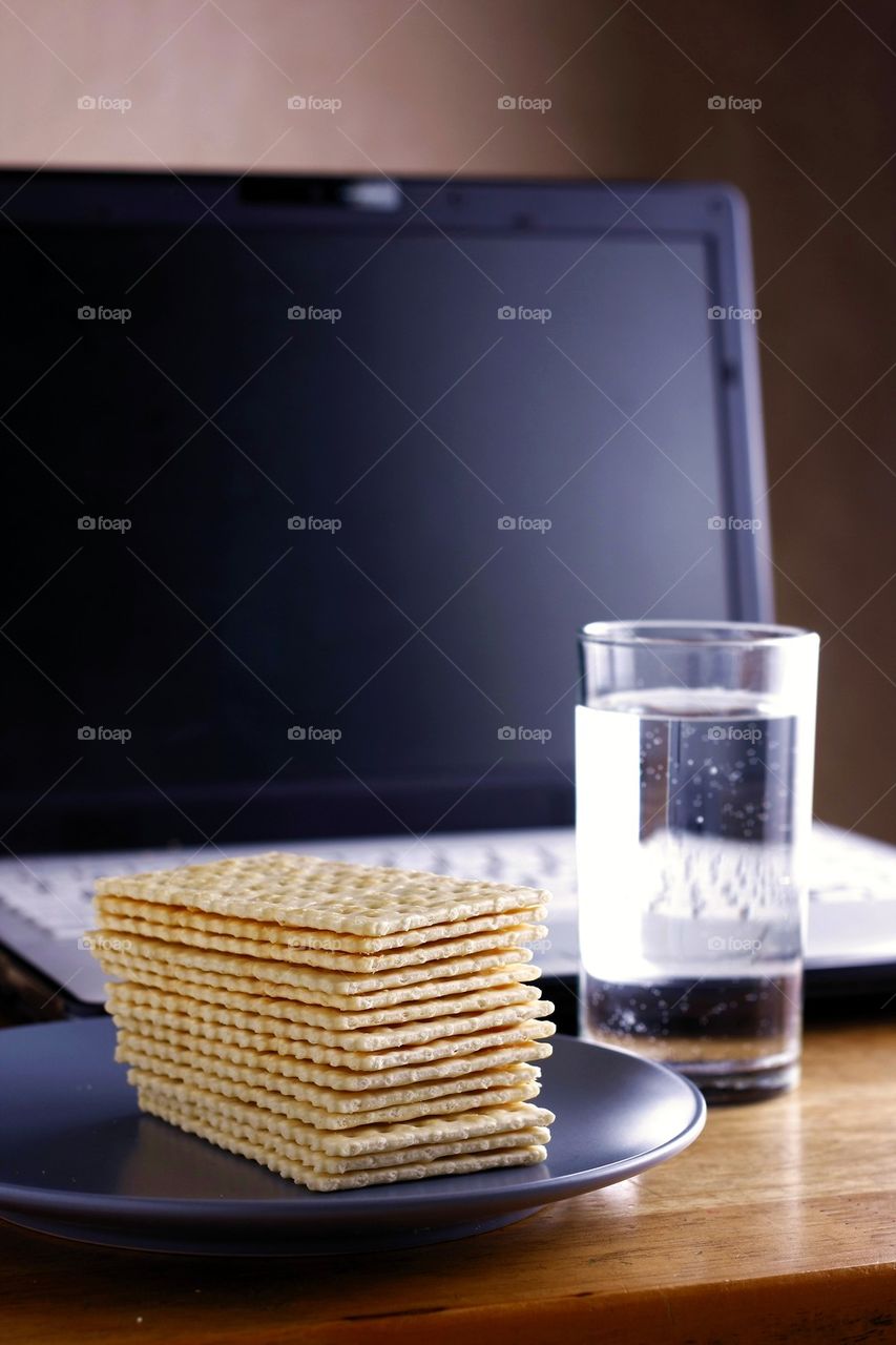 soda crackers, laptop computer and a glass of water