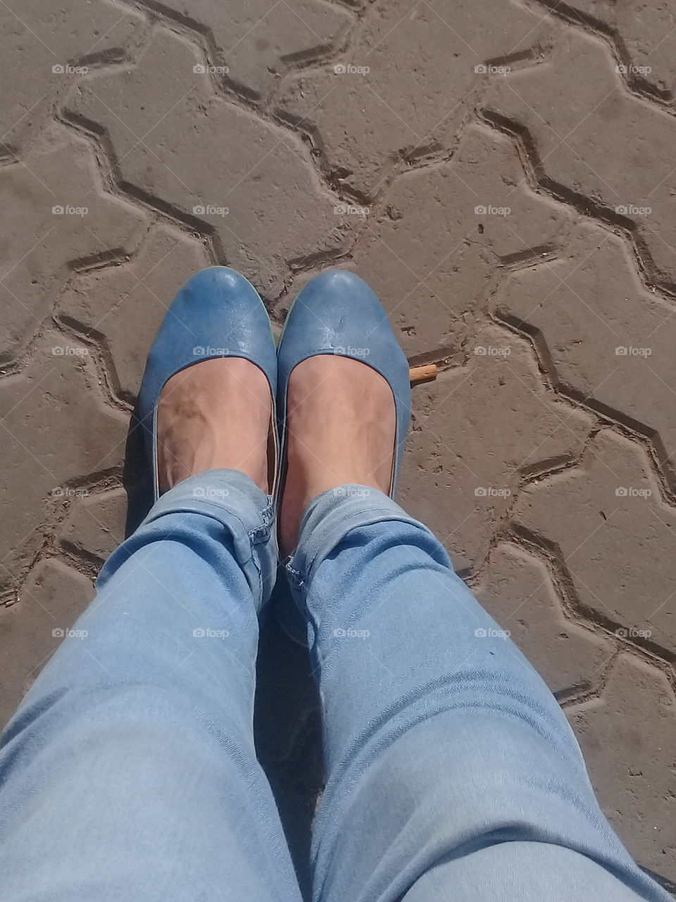 pies de dama calzados con zapatos bajos color azul, aplastando un cigarrillo sobre el pavimento
