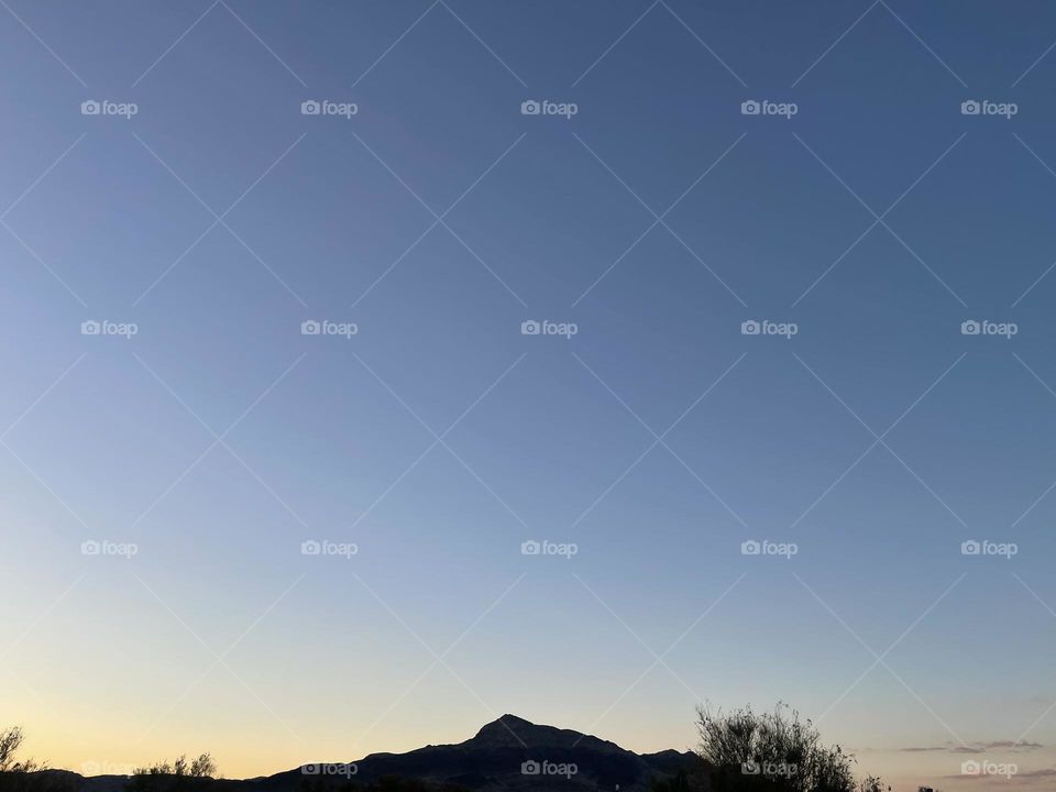 A yellow sunset with mountains and trees.