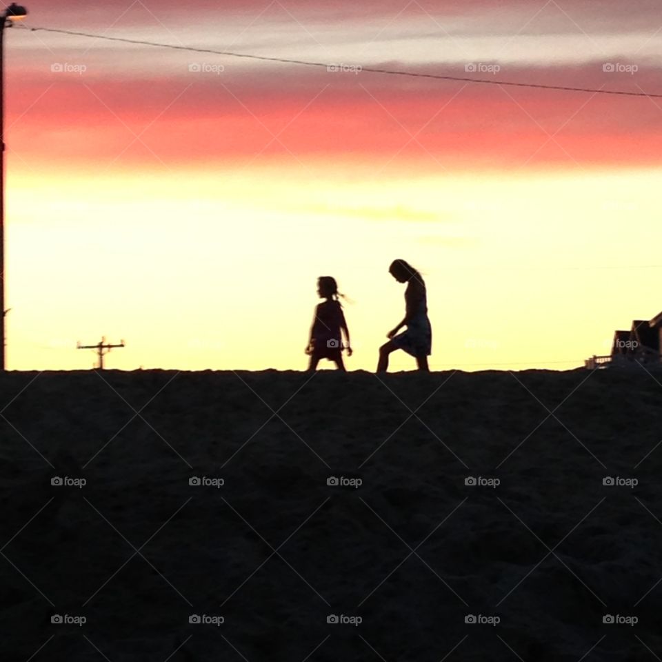 Follow me . Playing in the sand at sunset two sisters having fun 
