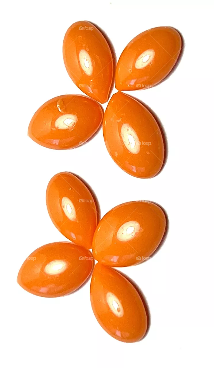 Orange granules of wax for depilation on white background.
