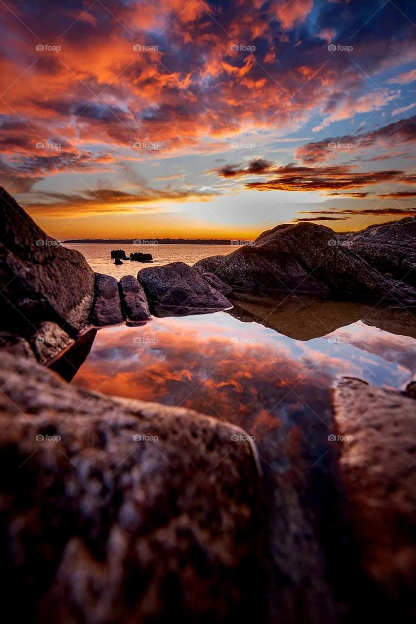 Colourful sunrise over the sea and the rocks in Moelan sur Mer, reflecting in the waters