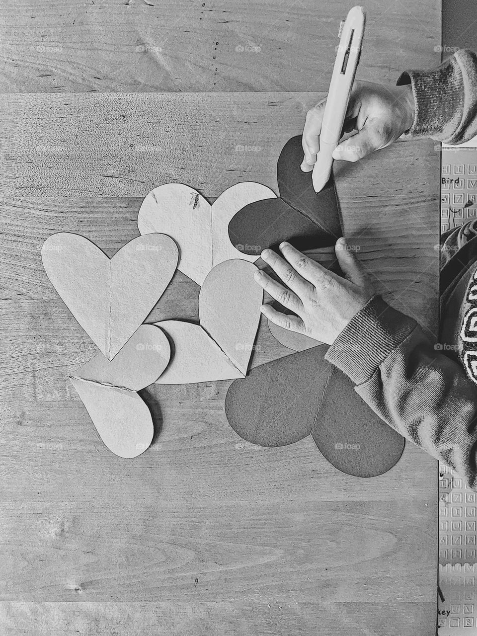 Black and white craft photo, hearts in monochrome, toddler playing with hearts, making valentines for friends and family, classic black and white image of love, crafting with love 