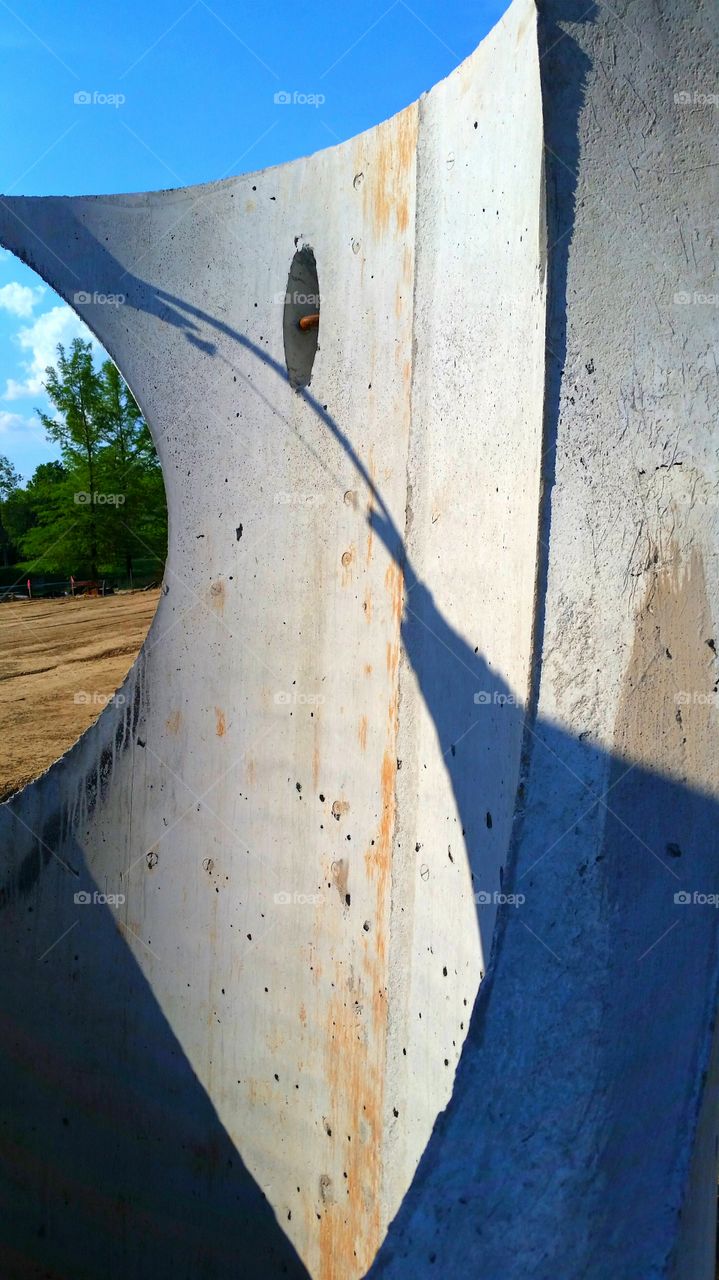 construction site, large concrete cylinder next to scraped dirt and trees