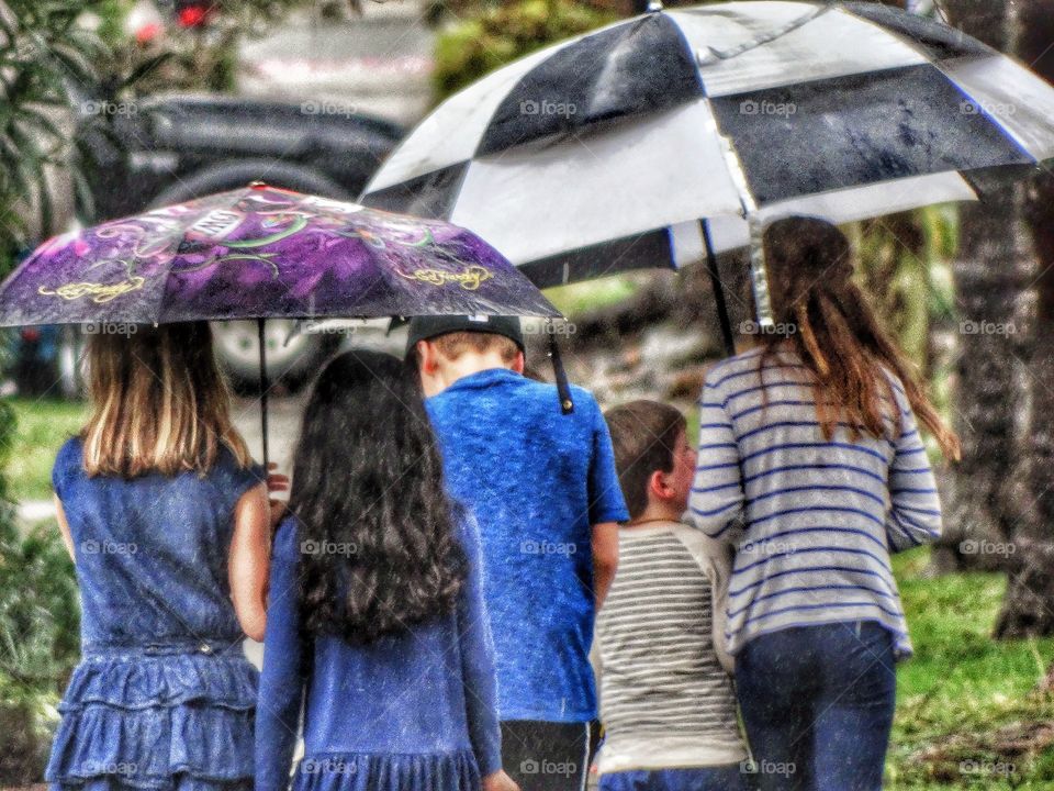 Kids Walking On The Sidewalk On A Rainy Day