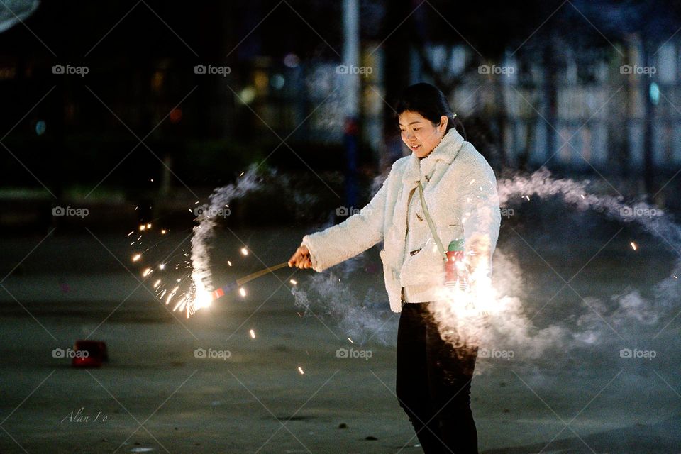 A Chinese lady playing firework at night happily 