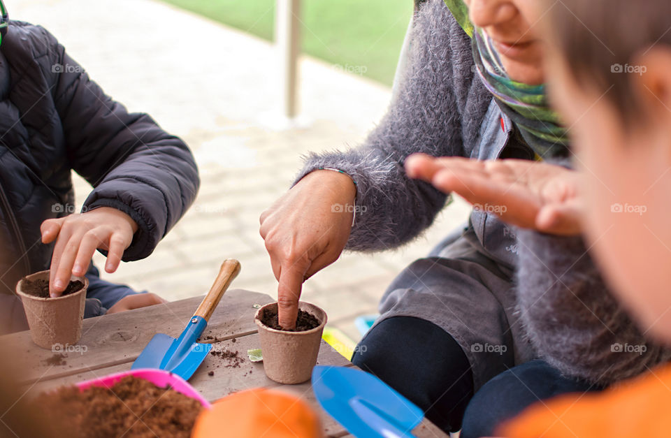 Mother teaches children how to plant seeds in the backyard of their home