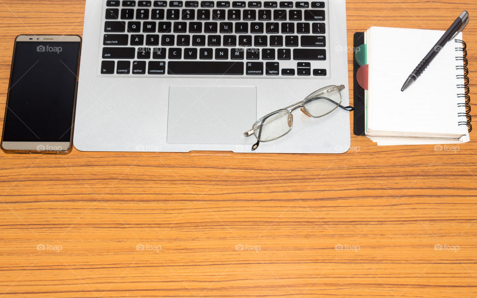 Desk with open notebook, mobile phone, eye glasses, placed on office table. Top view with copy space. Business still life concept with office stuff on table. Education, working or planning concept