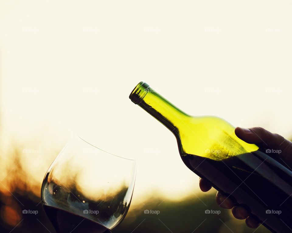 Person about to pour wine into wine glass