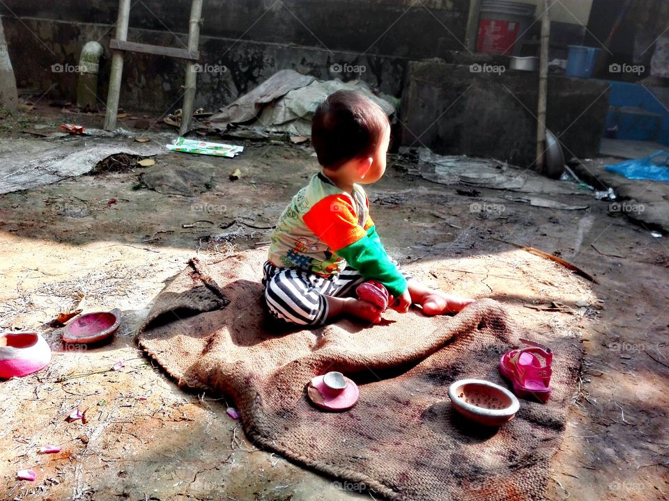 A Bangali Child Playing With it's Clay-built toys in Courtyard.