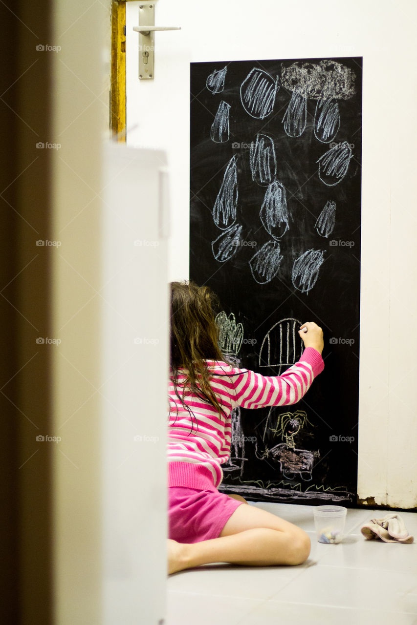 Fun at home - girl drawing on black board . We turned our kitchen door into an art corner and the kids love it! Image of girl drawing rain and girl playing with chalk on a blackboard.