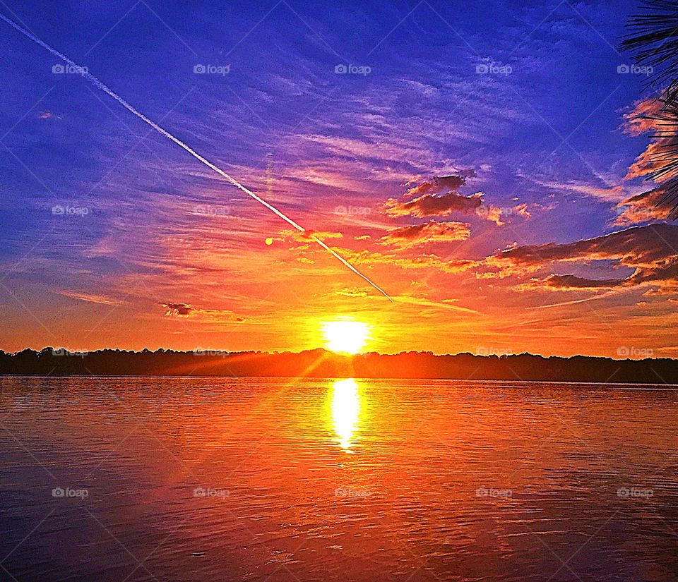 Sunrise, sunset and the moon  - Spectacular bright, explosive, and colorful sunset reflecting on the waters surface