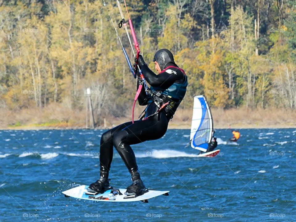 kiteboarder jumping into the air with windsurfing in background