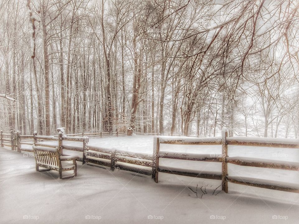 empty wooden bench in snowy rural landscape