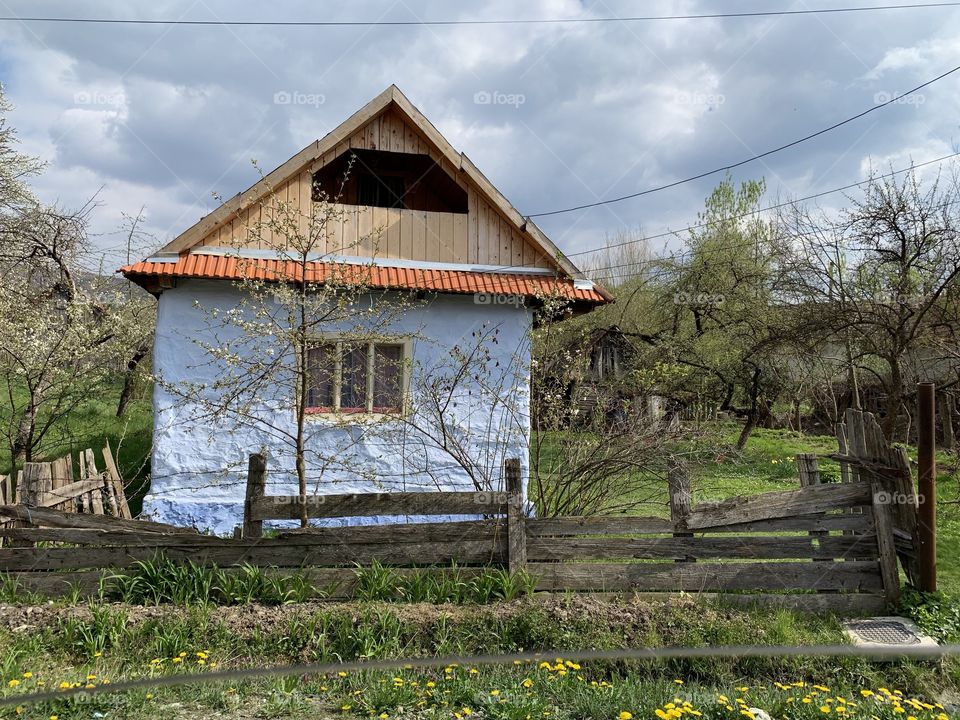 Colorful rural house at a village on countryside with green grass and cloudy sky 