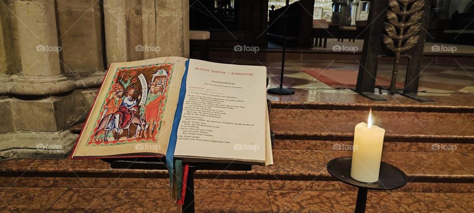 An antique illustrated version of the bible is placed open faced on a stand by the altar so the pastor can see it in the cathedral of “Regensburg” in the “Oberpfalz” in Germany. 2023. Hypnotic Productions