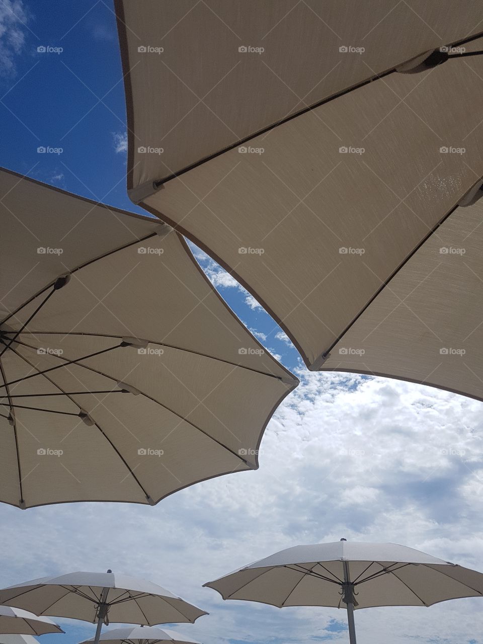 White beach umbrellas and cloudy blue sky in summer