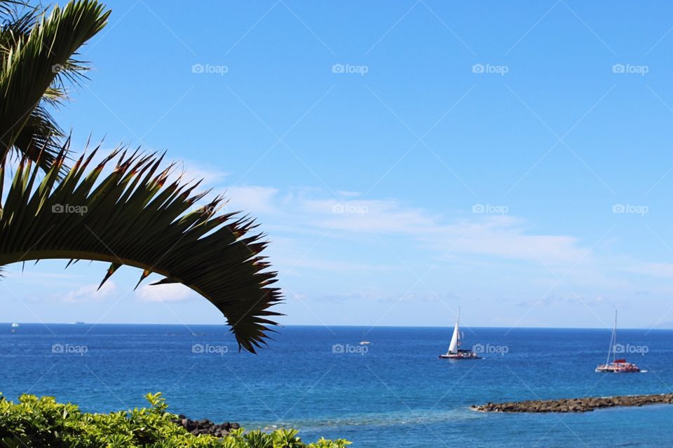 Turquoise ocean water with sailboats along the coast line of the Canary Islands, Spain.