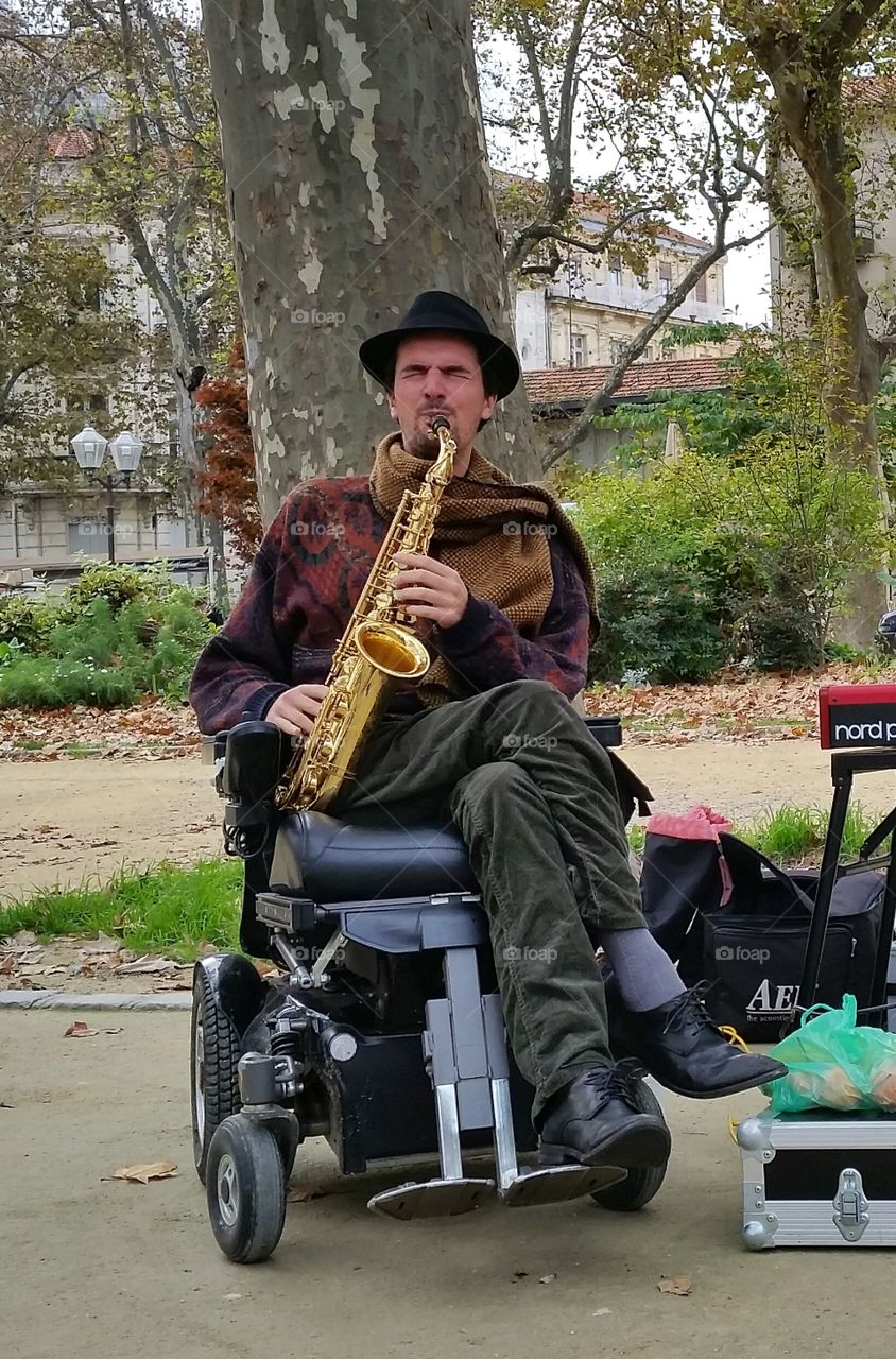 Disable man sitting on wheelchair playing saxophone