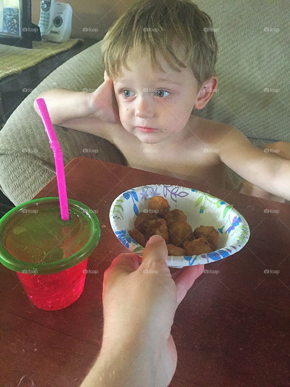 Human hand giving cheese balls to shirtless boy