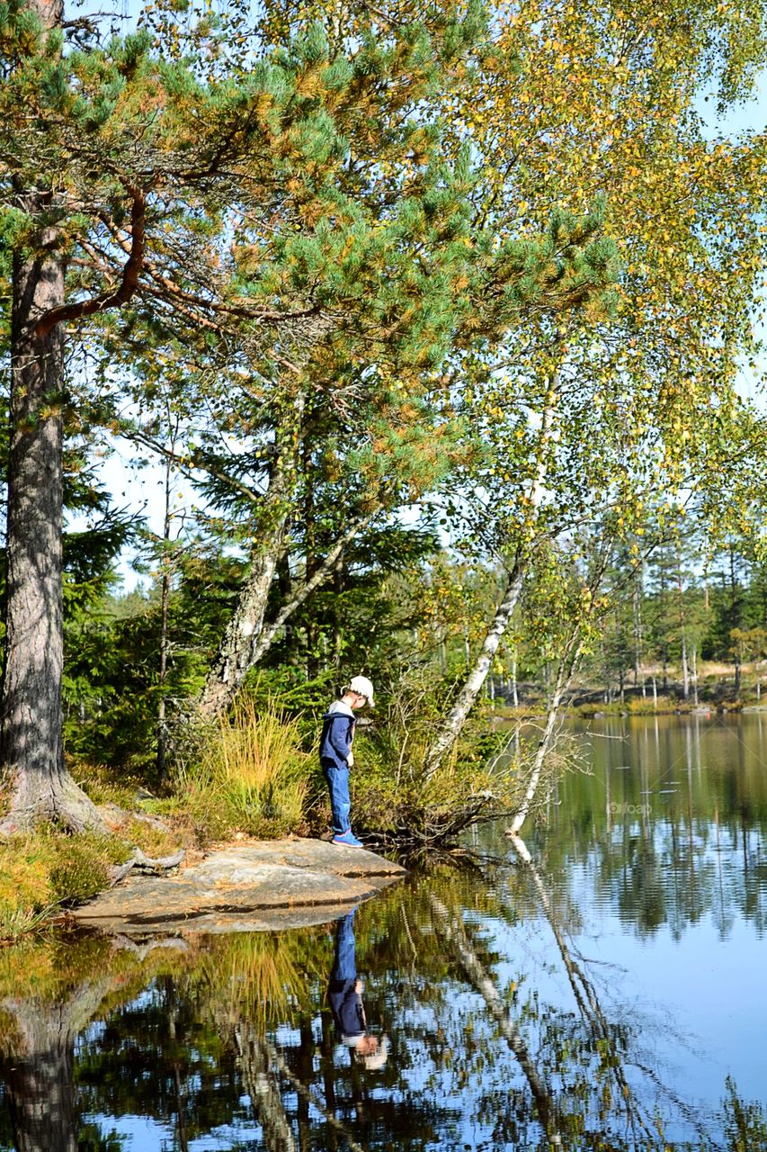 Little boy standing near lake