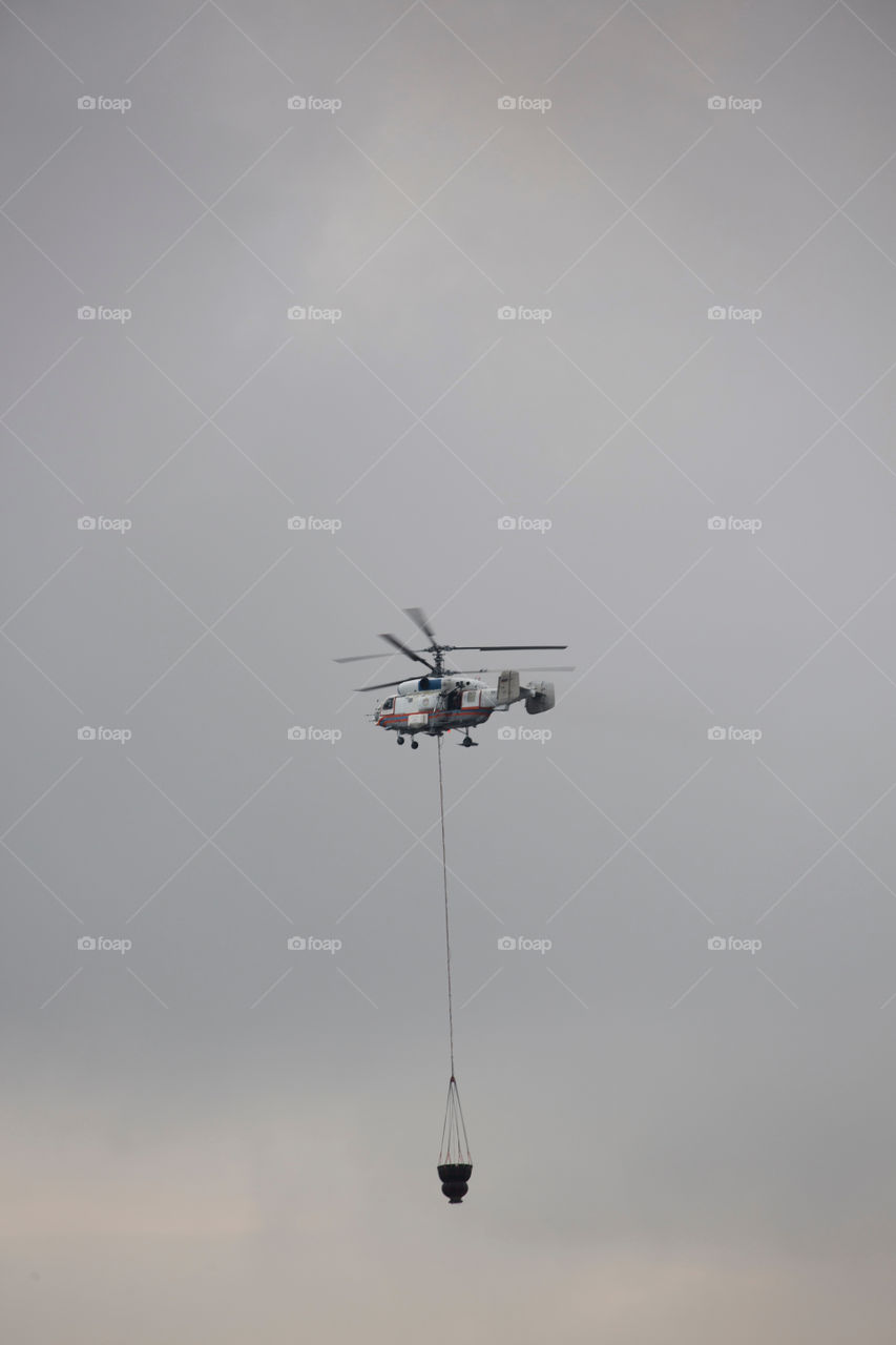 Helicopter of State Emergency Service is bringing the water in the bucket.