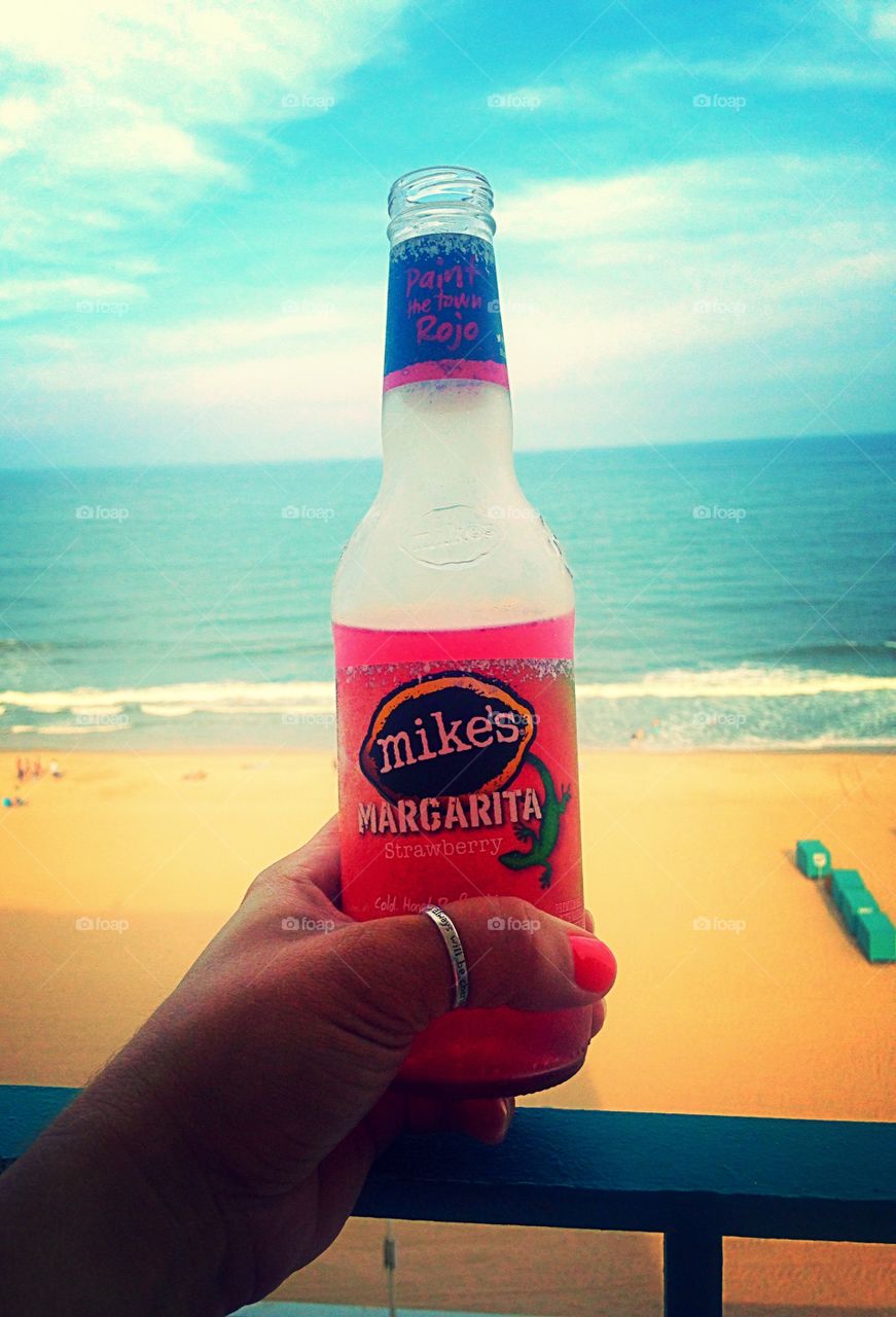 Paradise. Woman holding a drink on the balcony overlooking the ocean. 
