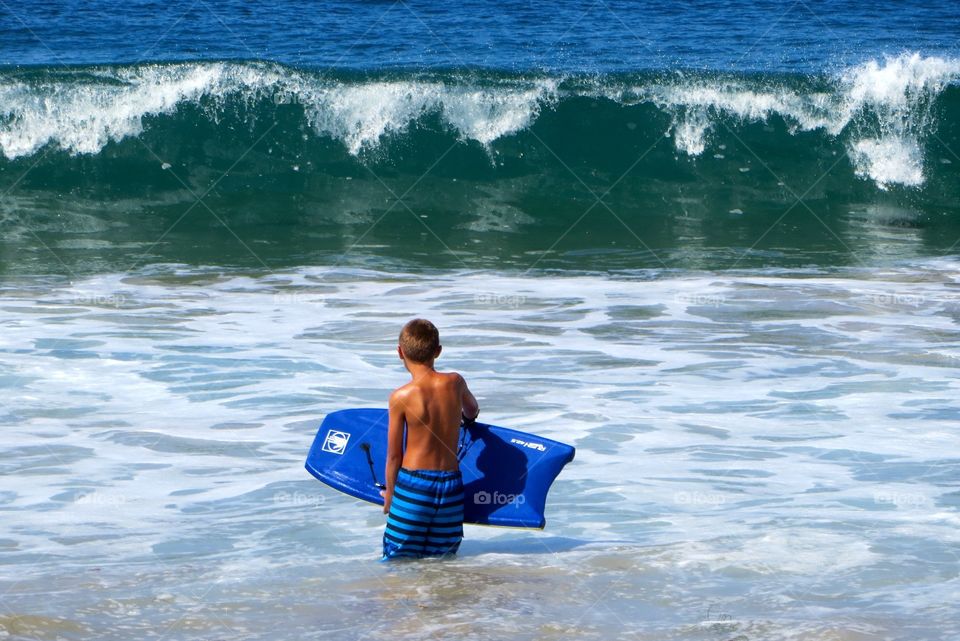 Contemplating The Surf. Boy heading out into surf