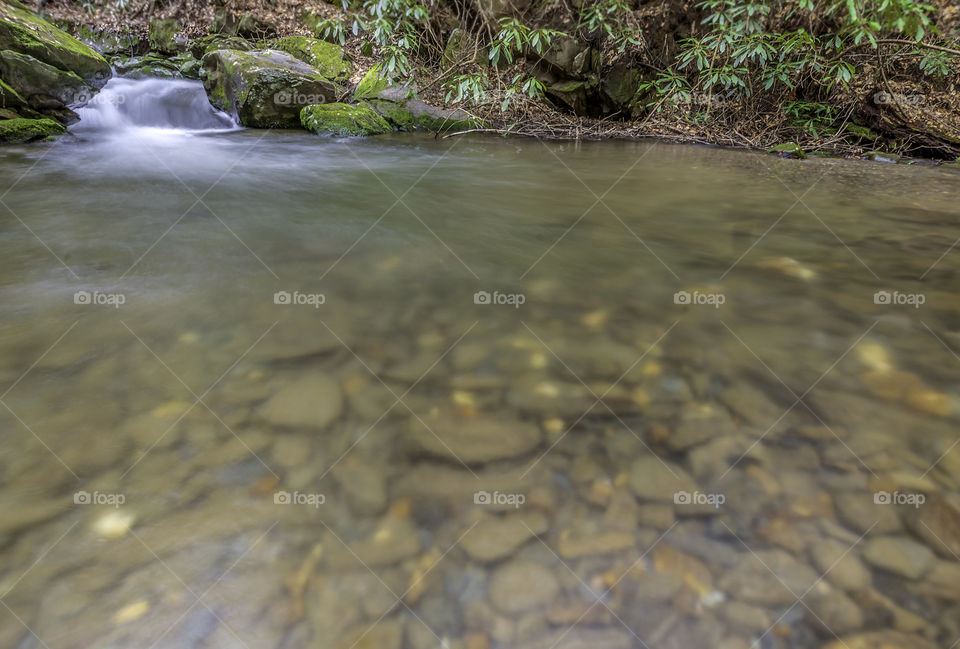 Wide angle long exposure of bear creek underwater stones and small waterfall