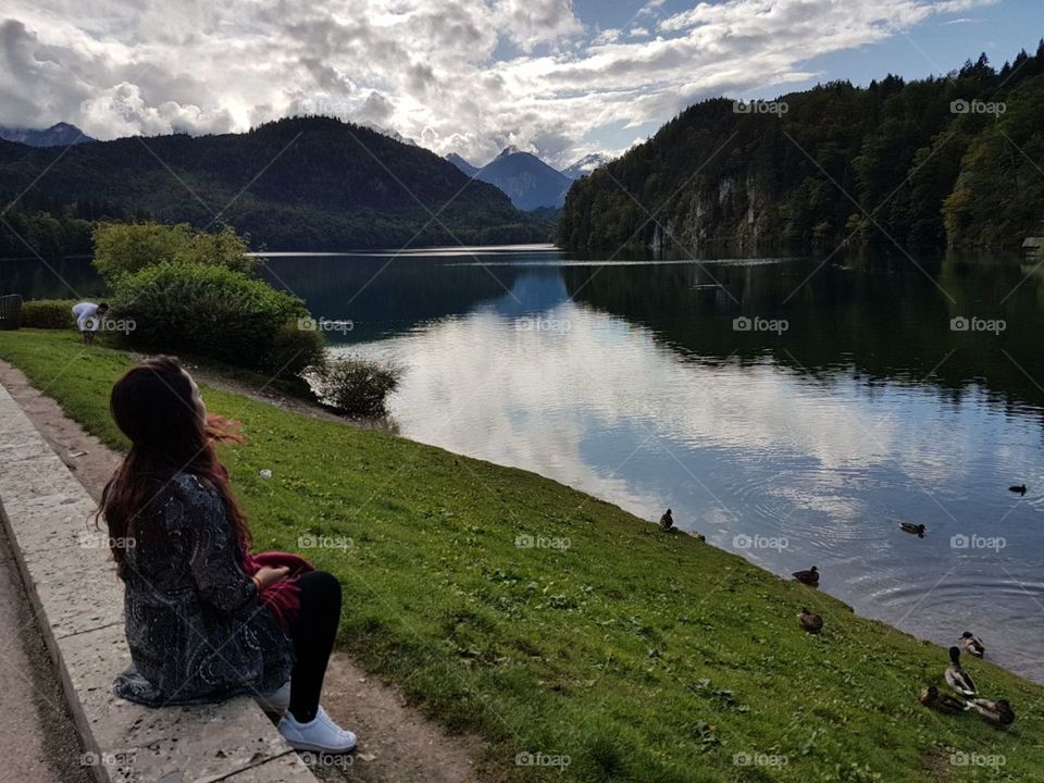 Füssen. View of the lake and mountains of fussen. It is possible to see the reflection of the trees and mountains in the lake and a woman admiring