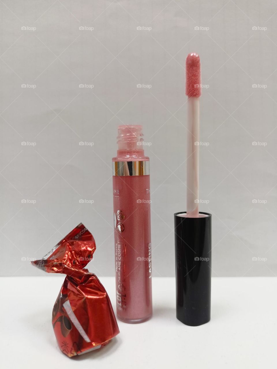 lip gloss, liquid lipstick, cosmetics, white background, chocolate candy in a wrapper