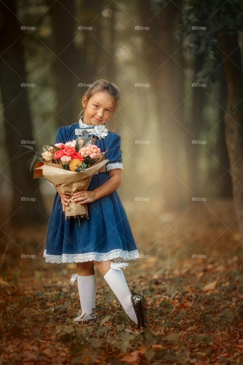 Little schoolgirl with a bouquet at a park 