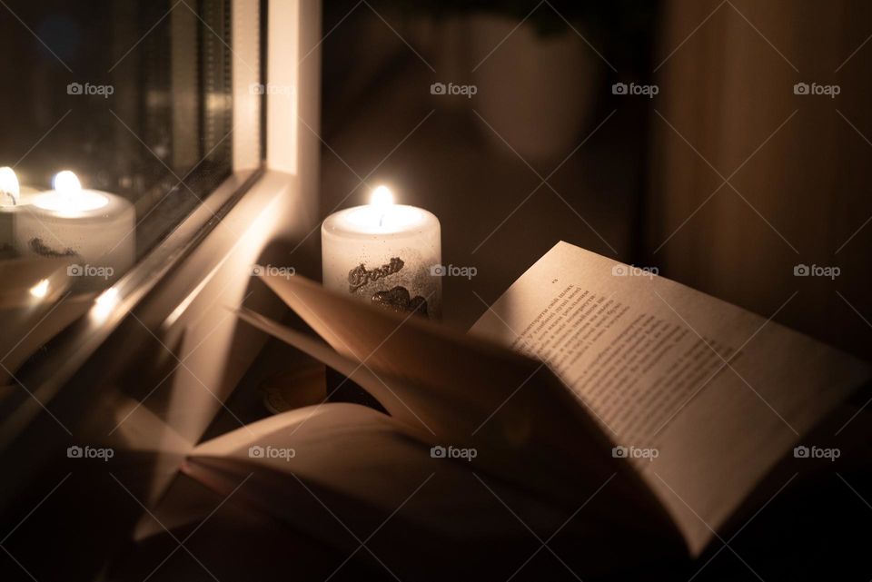 Reading a book at night over a candle by the window