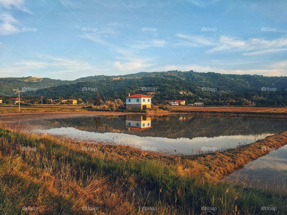 Scenic view of the beautiful reflection of the blue cloudy sky and a small farmer's house in a lake in autumn trip in Slovenia