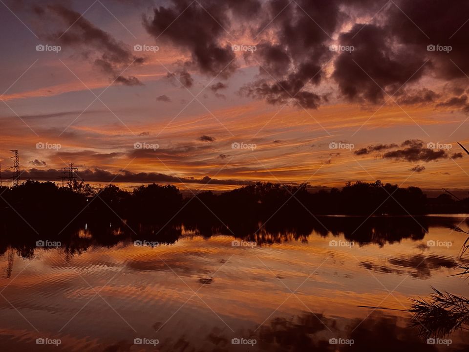 Sunset Colors blasting every direction With Reflections over Lake Waters of Entirety dividing border of the Landscape separates the Double Exposure. 