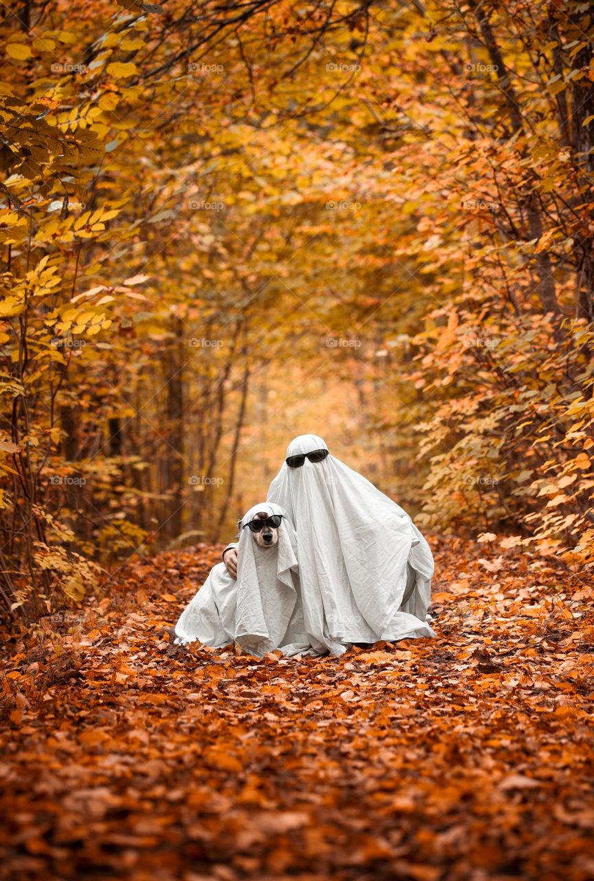 A dog and woman dressed up as ghosts 