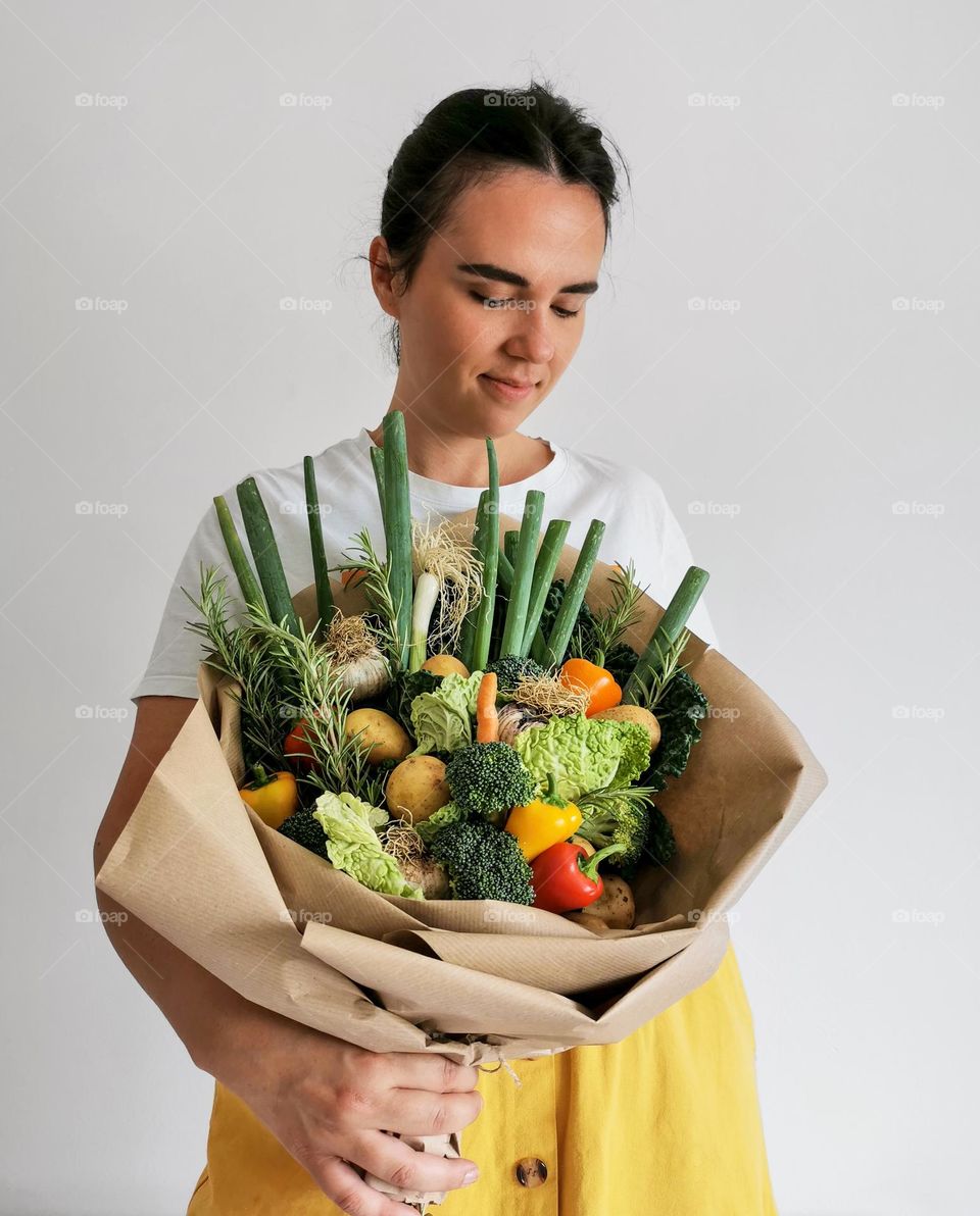 Portrait of young woman holding a bouquet made of vegetables