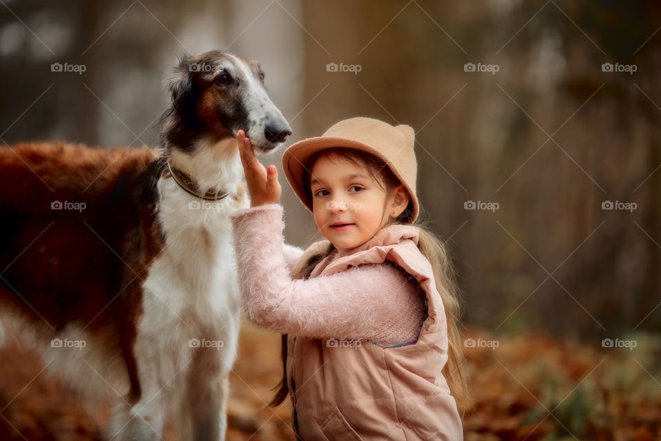 Cute smiling girl with borzoi dog in an autumn park 