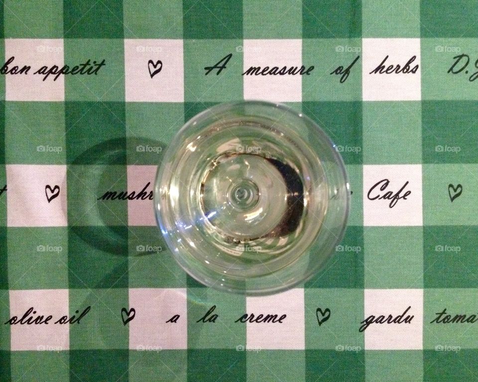 A glass of white wine on a table cloth in green and white squares 