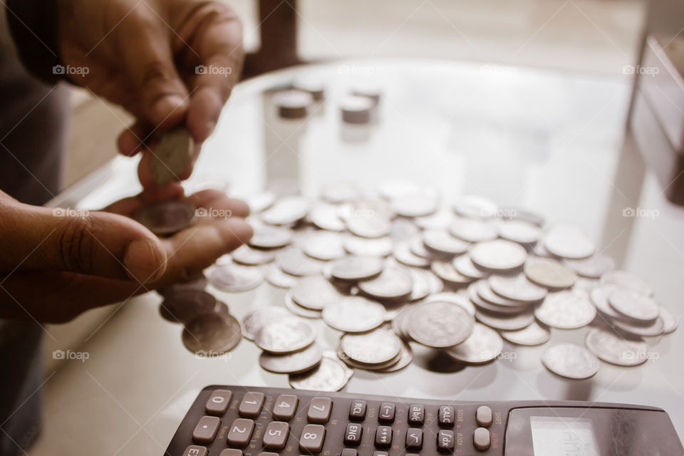 Cropped Image Of Businessman counting coins Using Calculator at Desk In Office. Businessperson Hand Counting Coins. Business Finance Savings and Investment concept. Conceptual Save money for future.