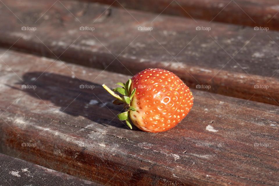 Fresh red strawberry on a wooden bench