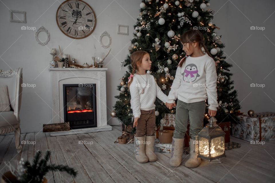 Little girls in wool boots near Christmas tree 